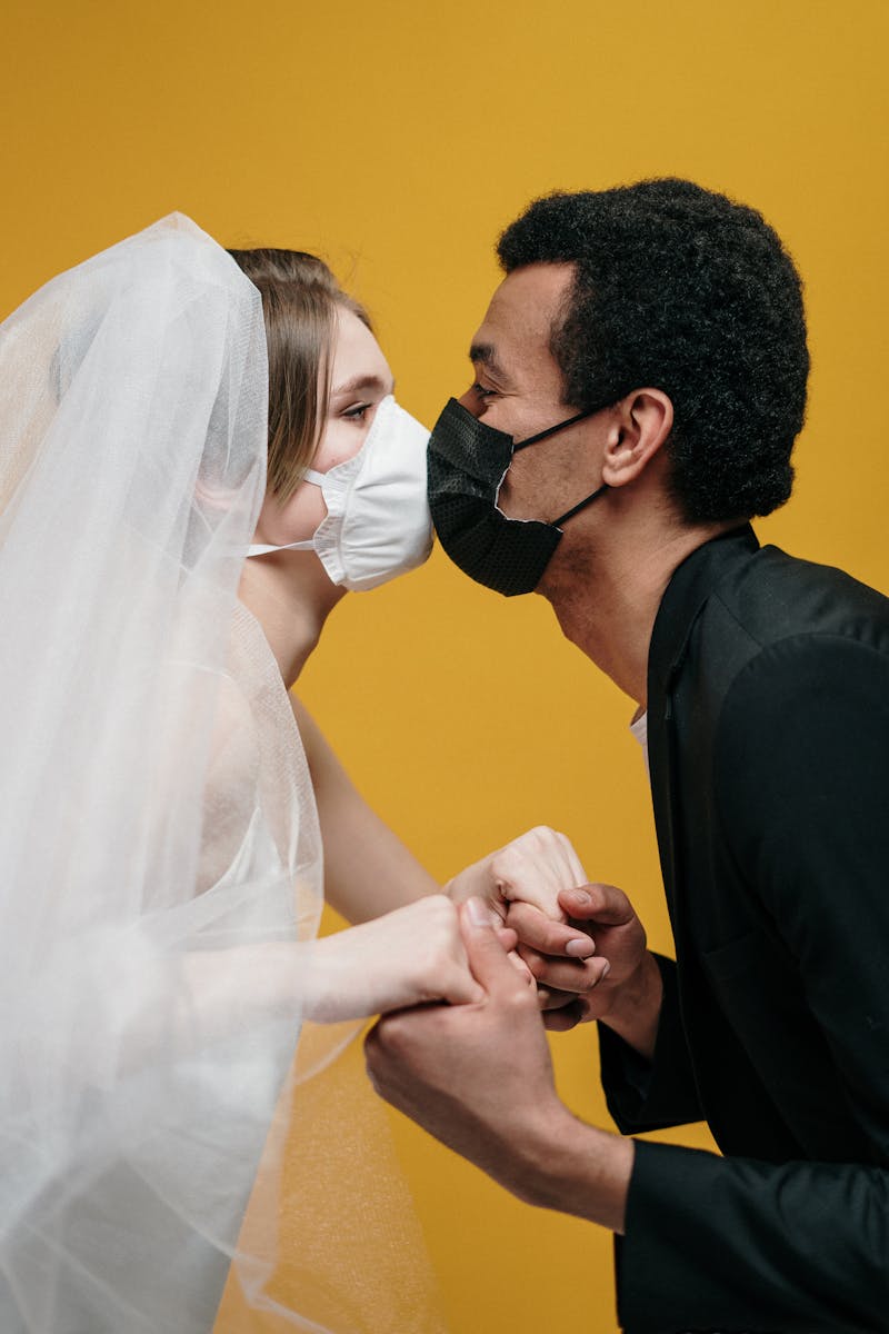 Bride and groom kissing with masks, illustrating pandemic love and protection.