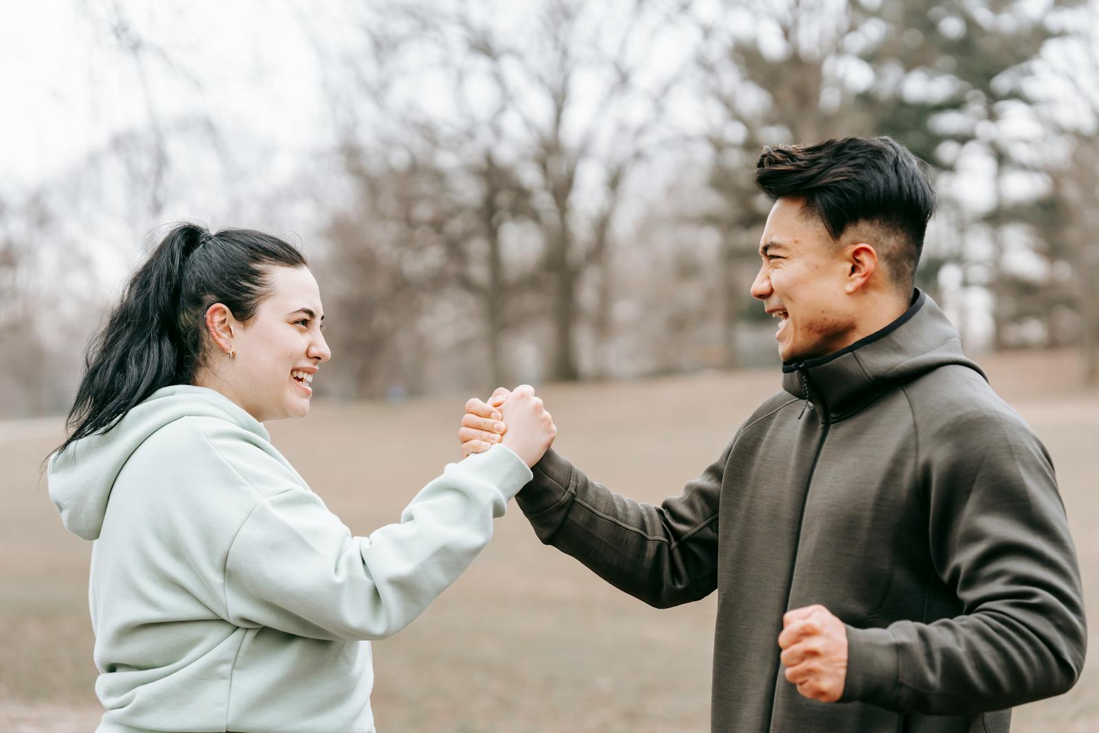 Two friends enjoying an outdoor workout session with a motivating handshake in a park.