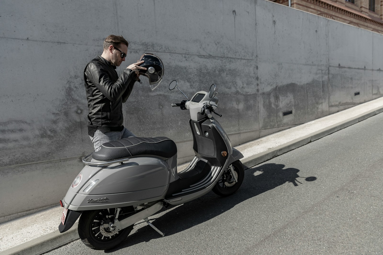 man in black jacket riding on gray motor scooter