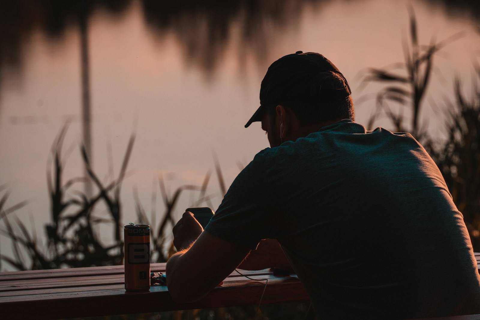 man in black shirt sitting on bench looking at the sunset