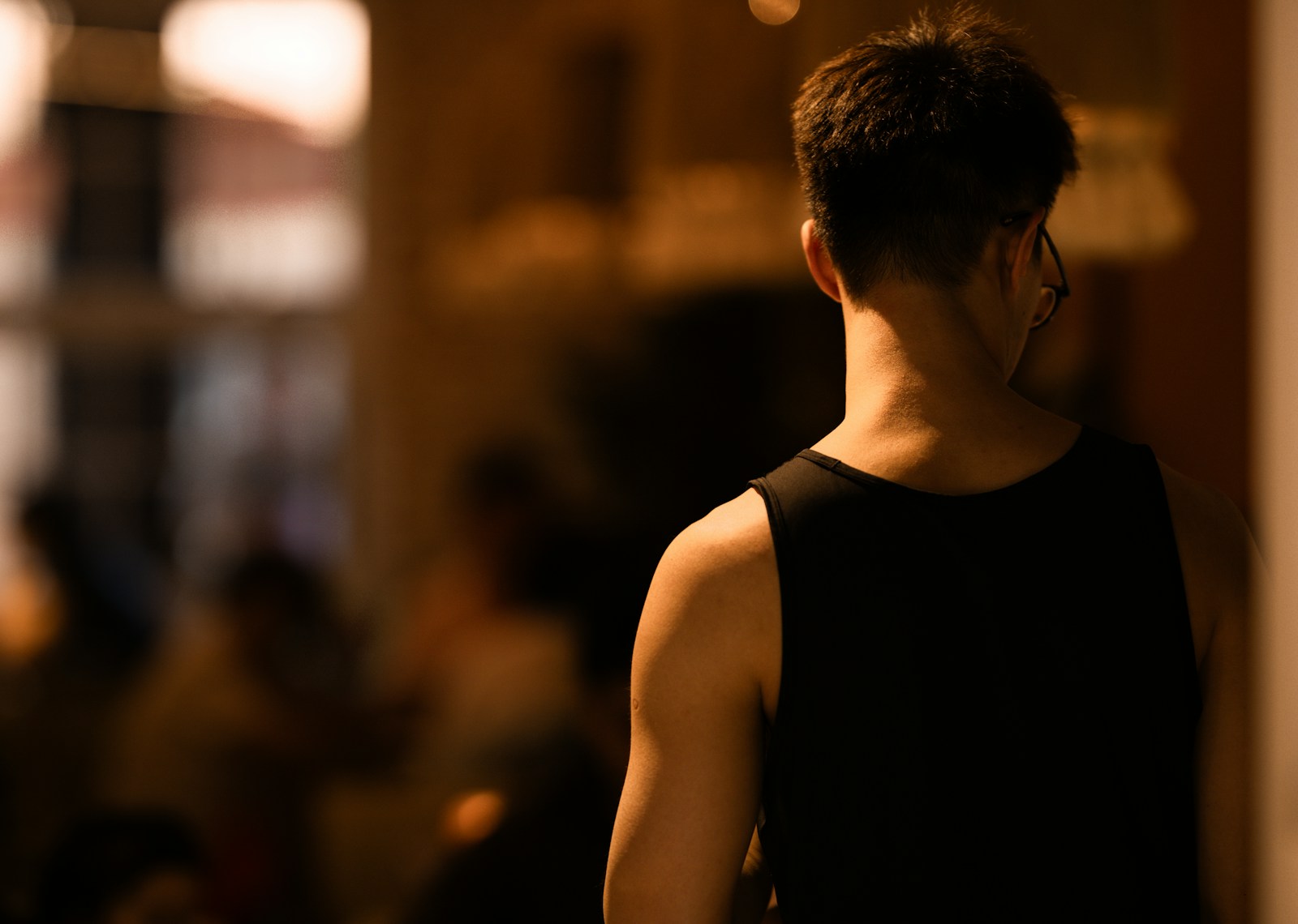 A man in a black tank top standing in a room