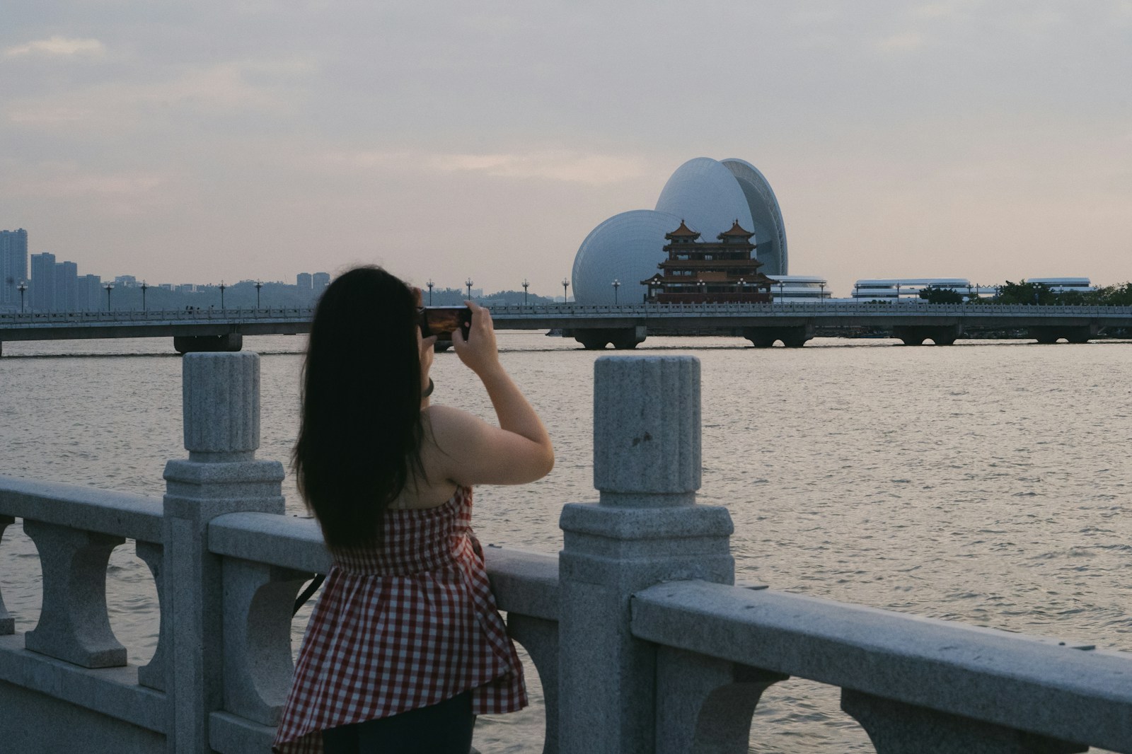 A woman standing on a bridge looking at the water