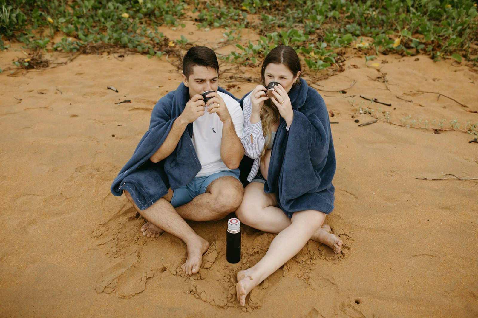 A man and a woman sitting in the sand